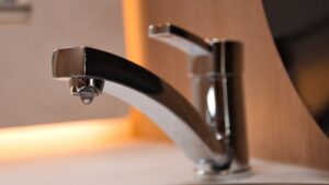 Leaky chrome faucet dripping water, a common cause of ants in kitchen sink
